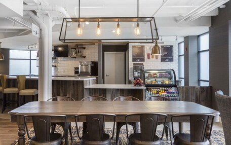 A modern kitchen with a bar area, wooden dining table, and bar stools.