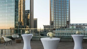A rooftop terrace with white round tables, chairs, and flower arrangements. - SpringHill Suites Charlotte City Center (Charlotte)