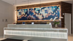 A reception desk with a modern design, featuring a wooden panel wall and a large abstract painting. - SpringHill Suites Charlotte City Center (Charlotte)