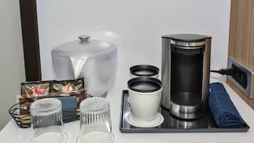 A kitchen setup with a coffee maker, a kettle, a coffee pot, and a tea kettle on a tray.