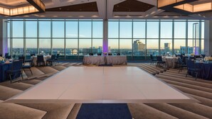 A spacious, modern event space with a large central area and multiple tables, large windows offering a city view, and a high ceiling with wooden beams. - SpringHill Suites Charlotte City Center (Charlotte)