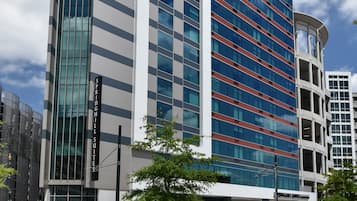 Un hôtel moderne doté d’une façade en verre remarquable, d’un toit rouge et d’un ciel bleu en arrière-plan.