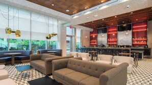 A modern lounge area with sofas, tables, and a bar with red lighting. - SpringHill Suites Charlotte City Center (Charlotte)