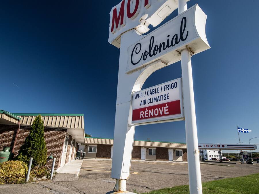 A motel sign with the name "Colonial" and amenities listed including Wi-Fi, cable, fridge, and air conditioning.