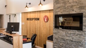 Un espace d’accueil avec un mur en bois, une horloge et un téléviseur fixé à un mur en pierre.