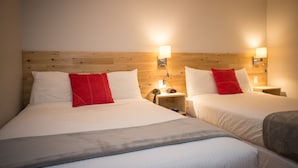 Une chambre d’hôtel avec deux lits, des têtes de lit en bois, des lampes de chevet et un téléphone sur la table de chevet.