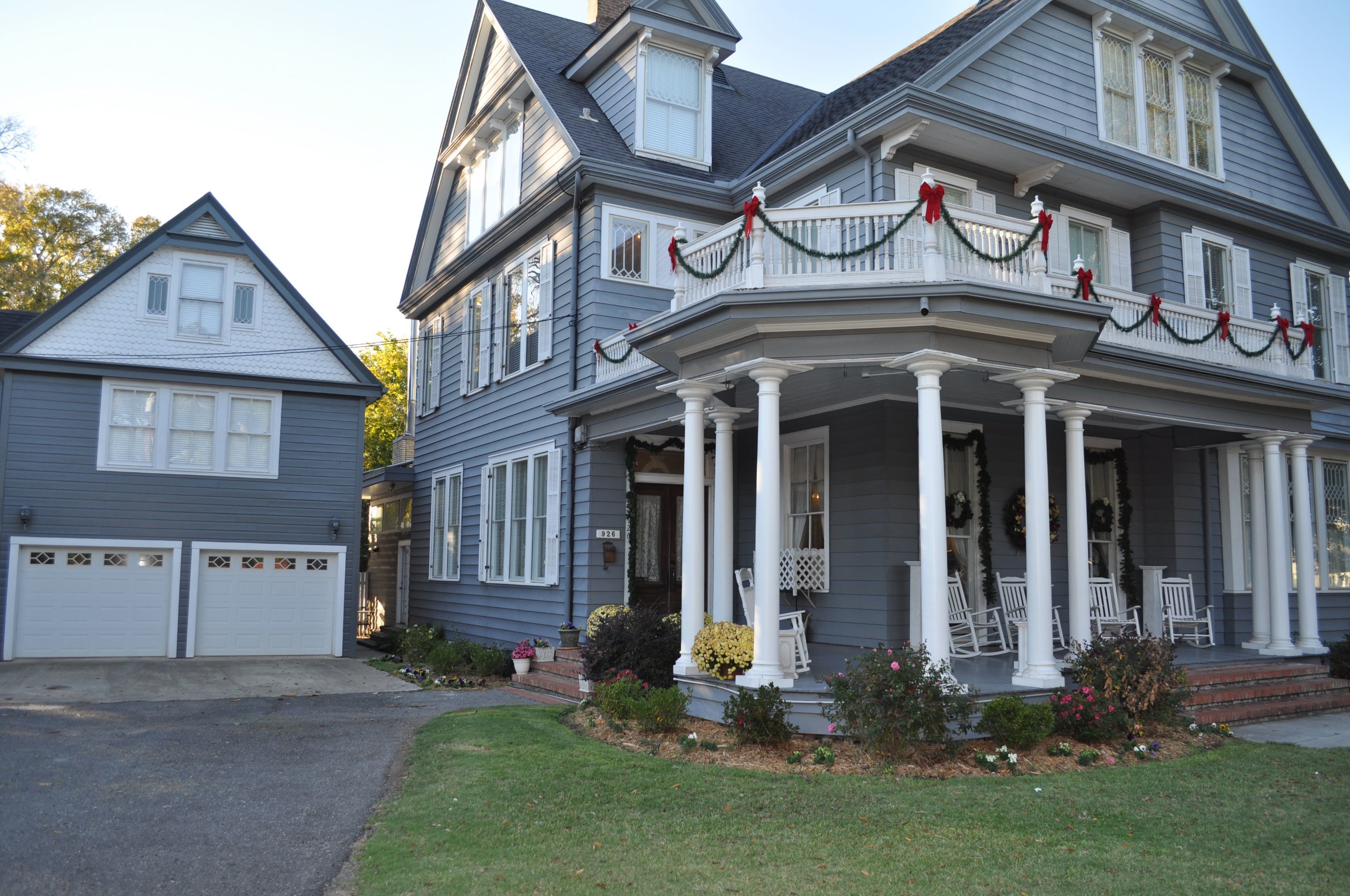 A two-story house with a porch, white columns, and a garage.
