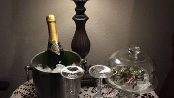 Una mesa con una botella de champán, una jarra de metal, un vaso y una cúpula de vidrio con comida.
