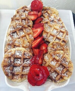 A waffle with strawberries and powdered sugar.