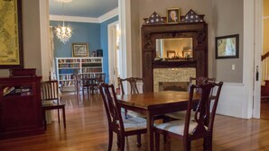 A dining room with a wooden table and chairs, a fireplace, and a bookshelf.