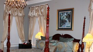A four-poster bed with a canopy, a chandelier, and a painting on the wall.