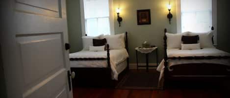 Une chambre avec deux lits simples, une petite table et deux lampes fixées au mur.