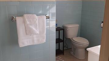 A bathroom with a blue tiled wall, a white toilet, a sink, and a towel hanging on a rack.