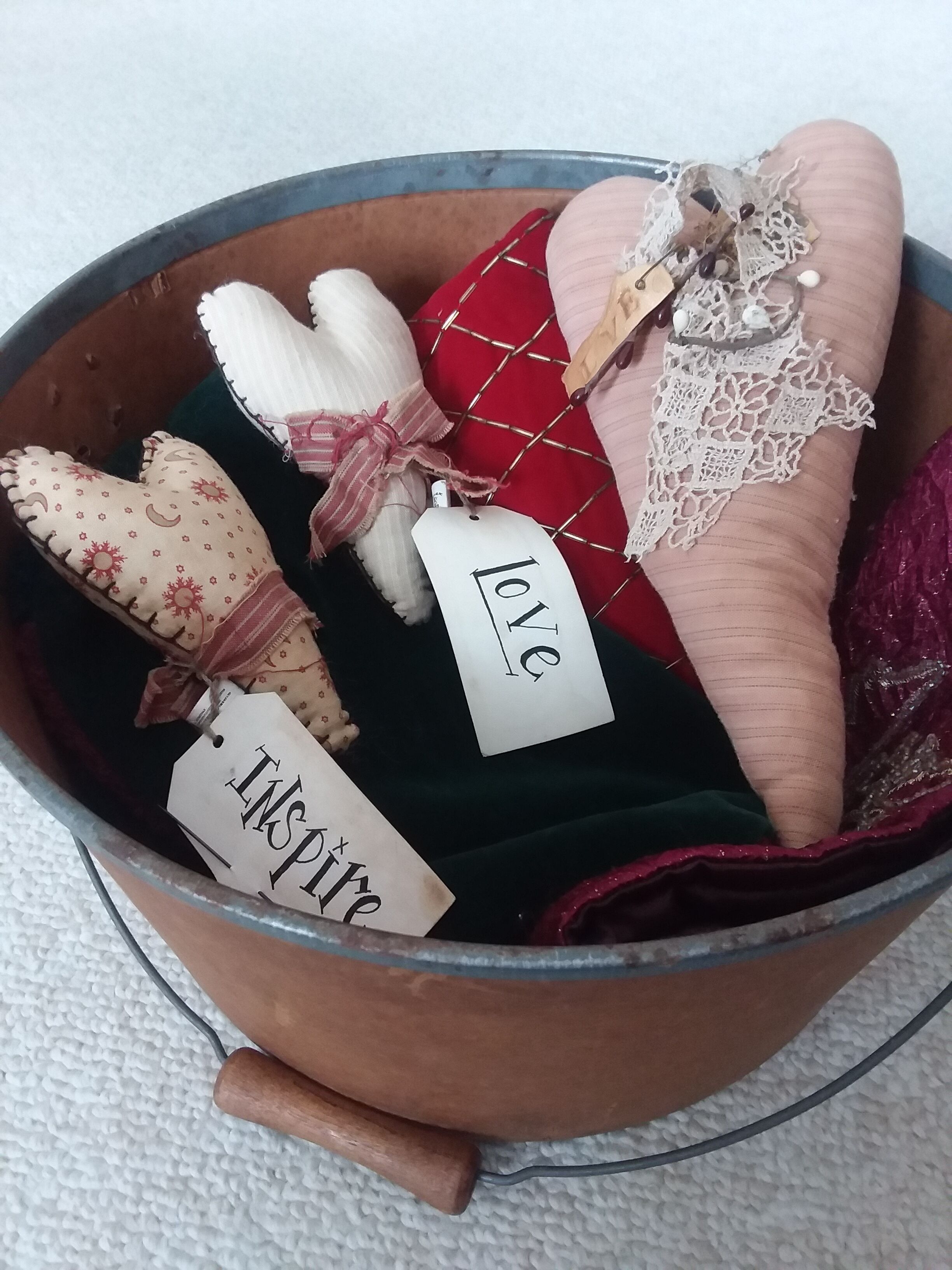 A metal bucket containing various decorative items with tags labeled "love" and "inspire."