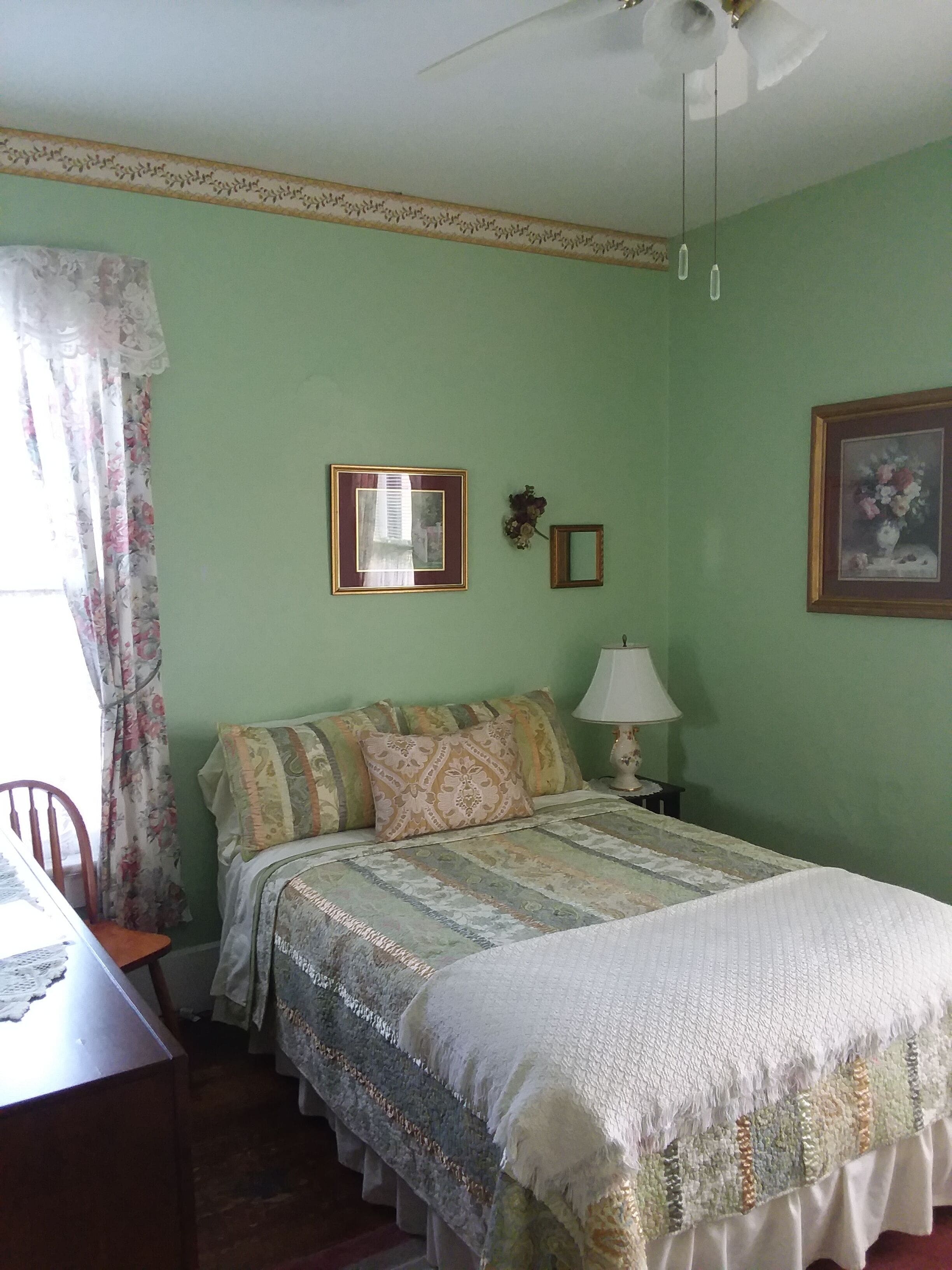 Un dormitorio con una cama, una silla, una mesa y una lámpara.