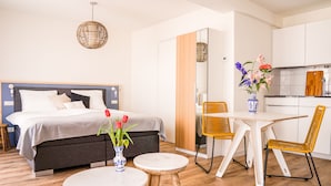A modern bedroom with a bed, bedside table, and a vase with flowers. - Boulevard 5 (Zandvoort)