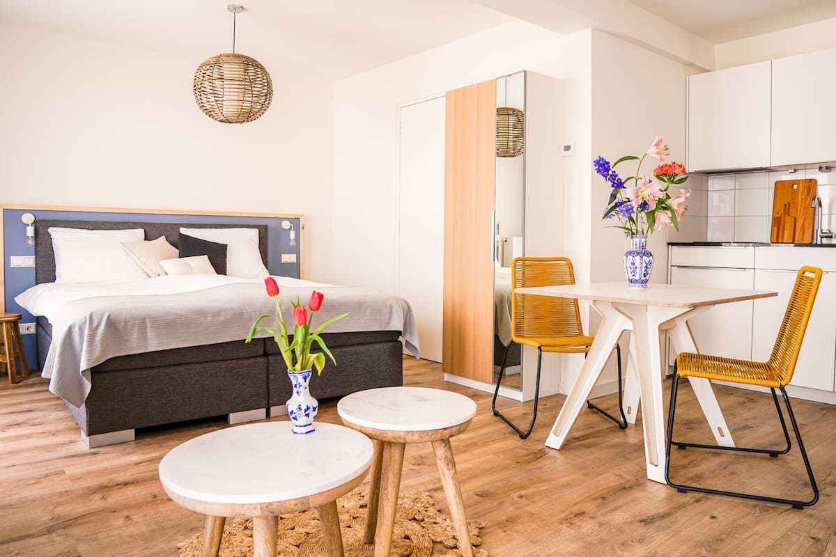 Un dormitorio moderno con una cama, una mesita de noche y un florero con flores.