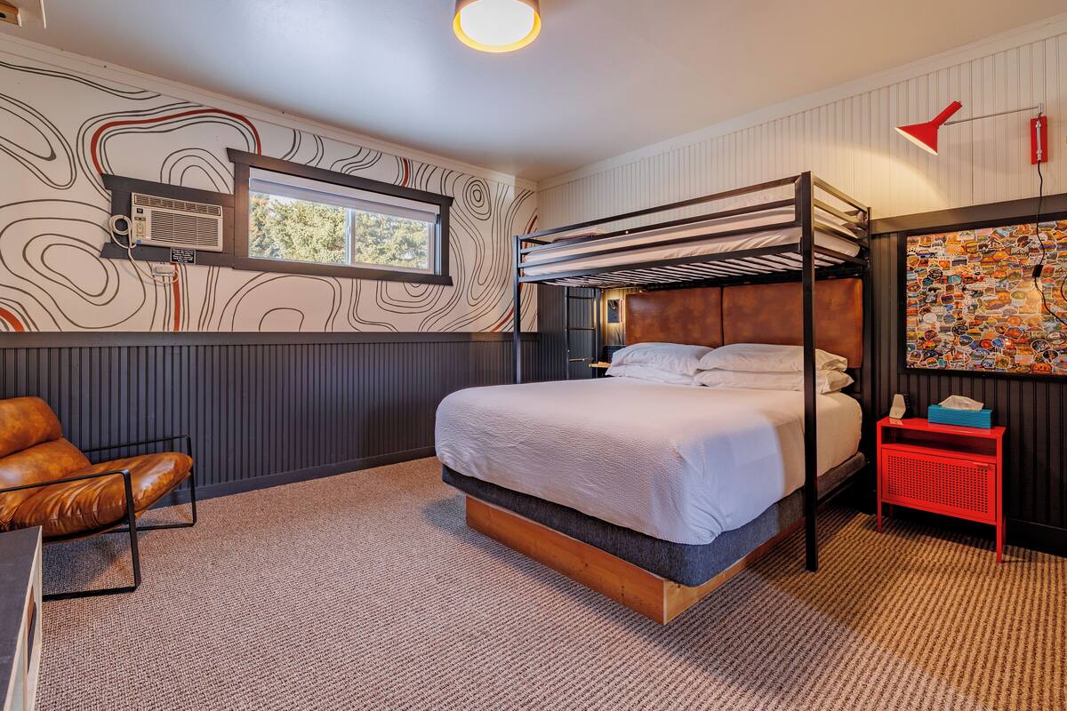 Ein modernes Schlafzimmer mit Etagenbett, Ledersessel, Schreibtisch und einer Wand mit außergewöhnlichem Design.