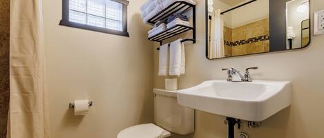 A bathroom with a toilet, sink, towel rack, and a window.