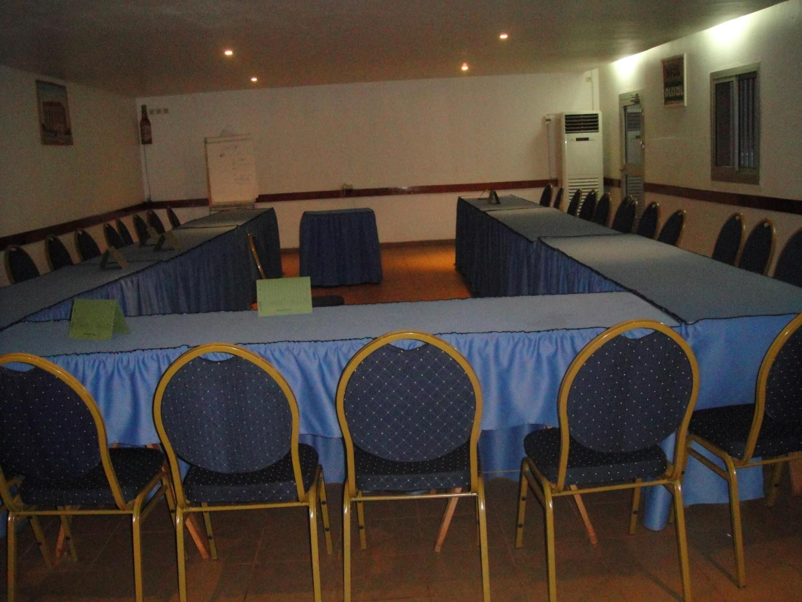 Une salle de conférence équipée d’une longue table et de chaises, d’un tableau blanc et d’un appareil de climatisation.