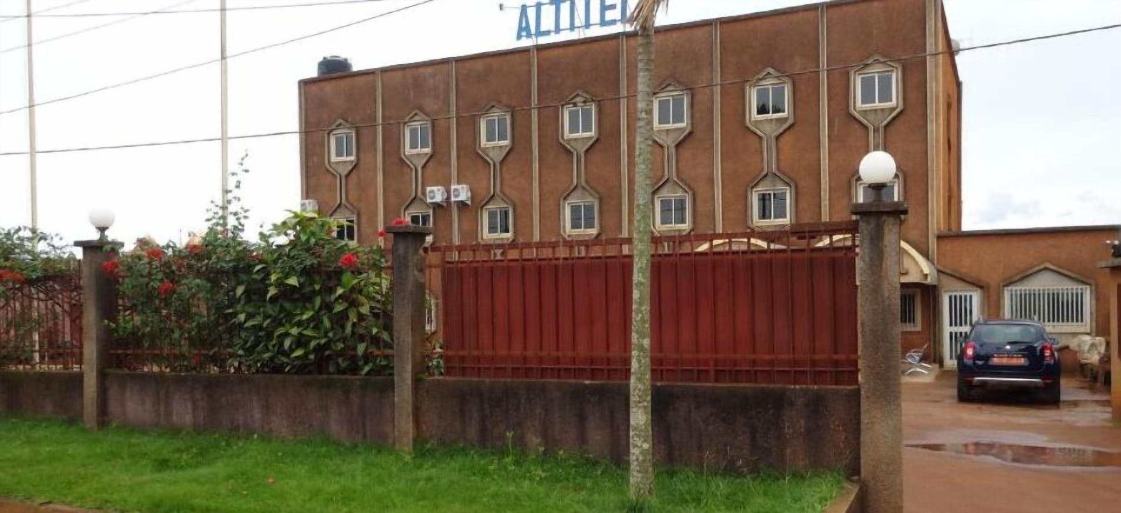 A building with a brown facade, multiple windows, and a red gate.