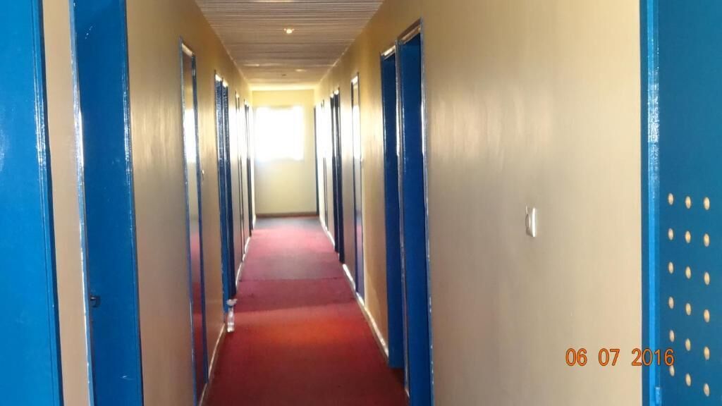 A hotel corridor with blue doors and a red carpet.