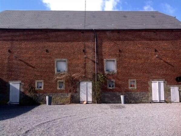 A brick building with multiple small windows and doors, a gravel driveway, and a clear sky. - Maison D'eclaibes (Eclaibes)
