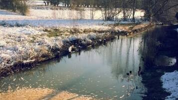 A calm river with snow-covered banks and sparse vegetation.
