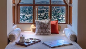Un rincón acogedor para sentarse con vistas a un paisaje montañoso a través de una ventana con un marco de madera decorativo.
