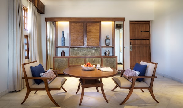 Un comedor con una mesa redonda de madera, dos sillas y un aparador decorativo con jarrones.