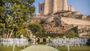 Un castillo en una colina con un césped y sillas blancas al frente.