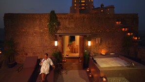 Un área de spa con pared de piedra, una bañera y una tumbona.