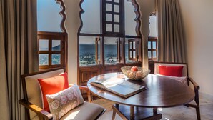 Una habitación con vistas al mar, una mesa redonda de madera y dos sillas con cojines.
