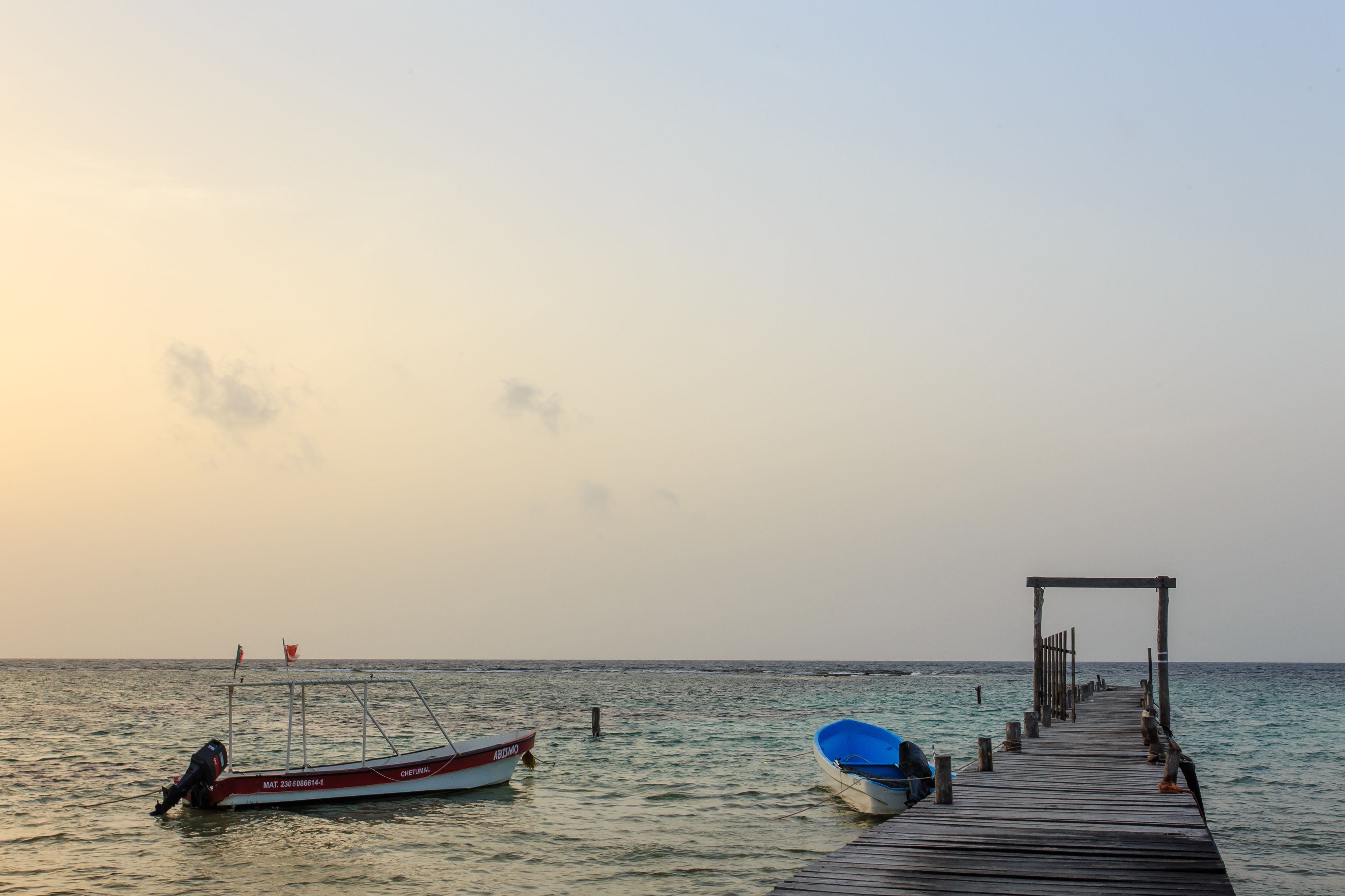 A pier extending into calm waters with a boat docked at the end.