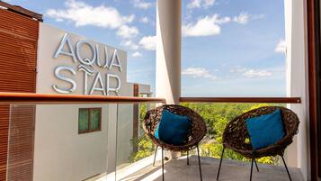 Un balcón con dos sillas de mimbre, un letrero que dice "AQUA STAR" y vista a zonas verdes.