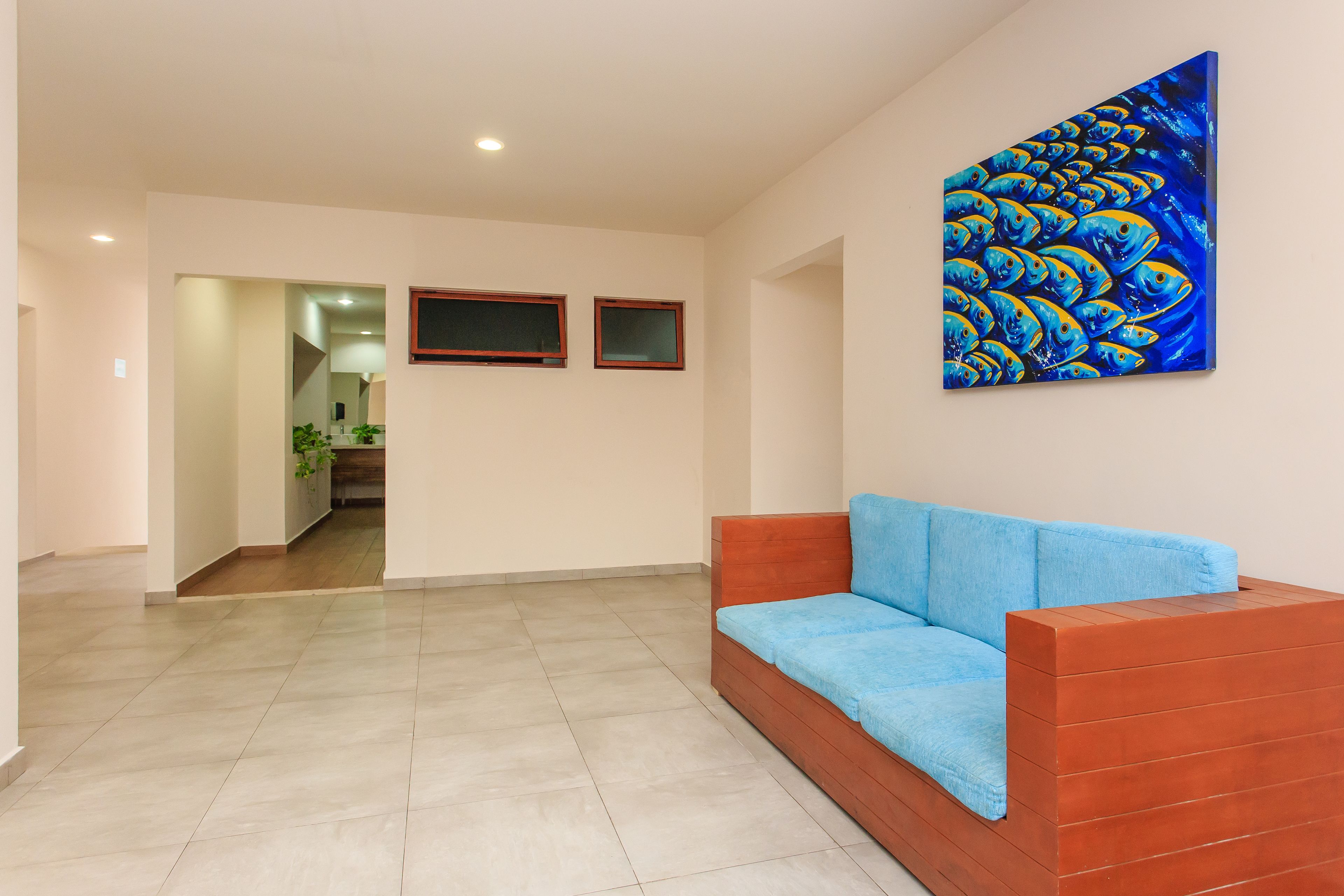 A modern living room with a blue sofa, a large abstract painting, and a hallway leading to another room.