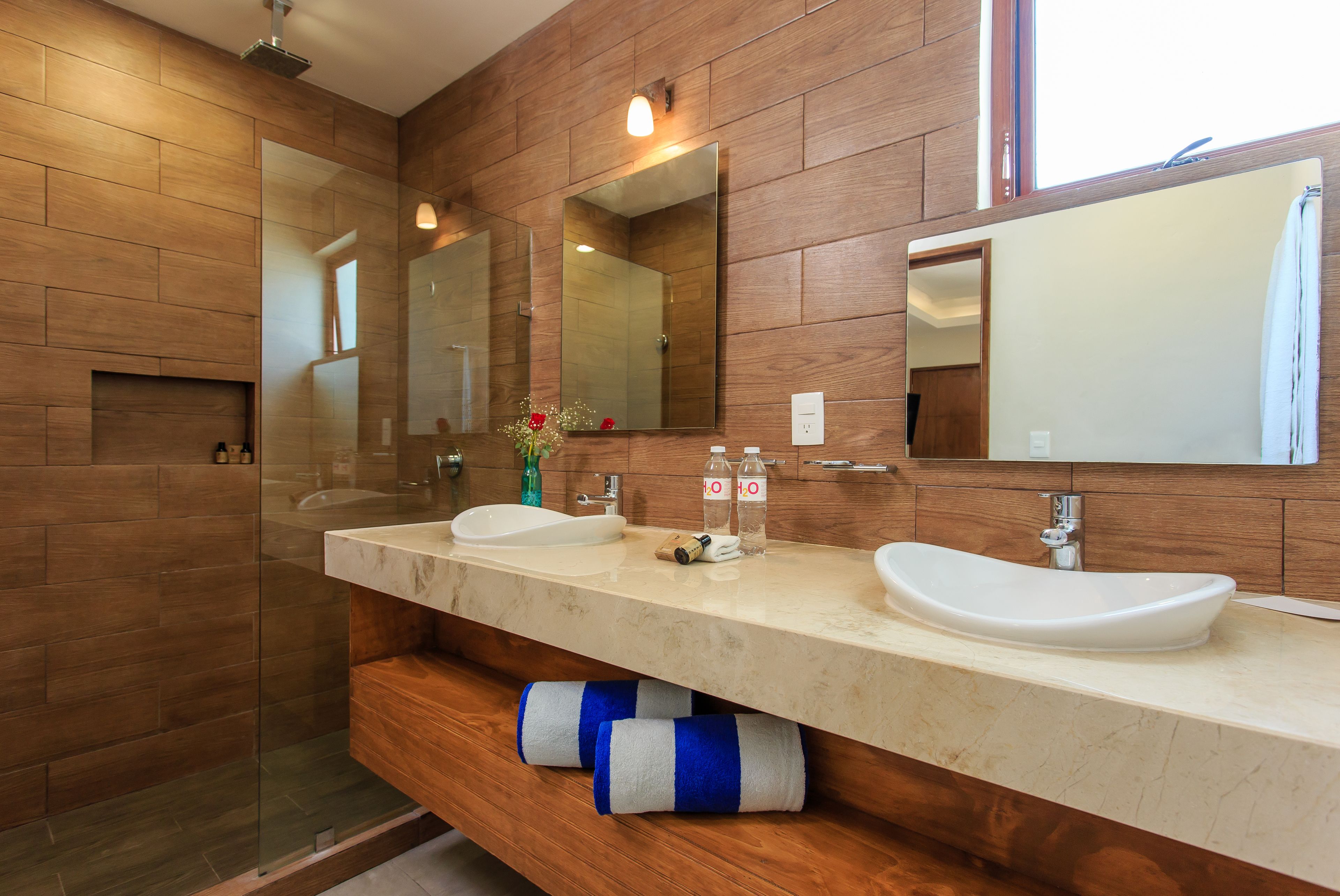 A modern bathroom with wooden walls, two sinks, and a large mirror.