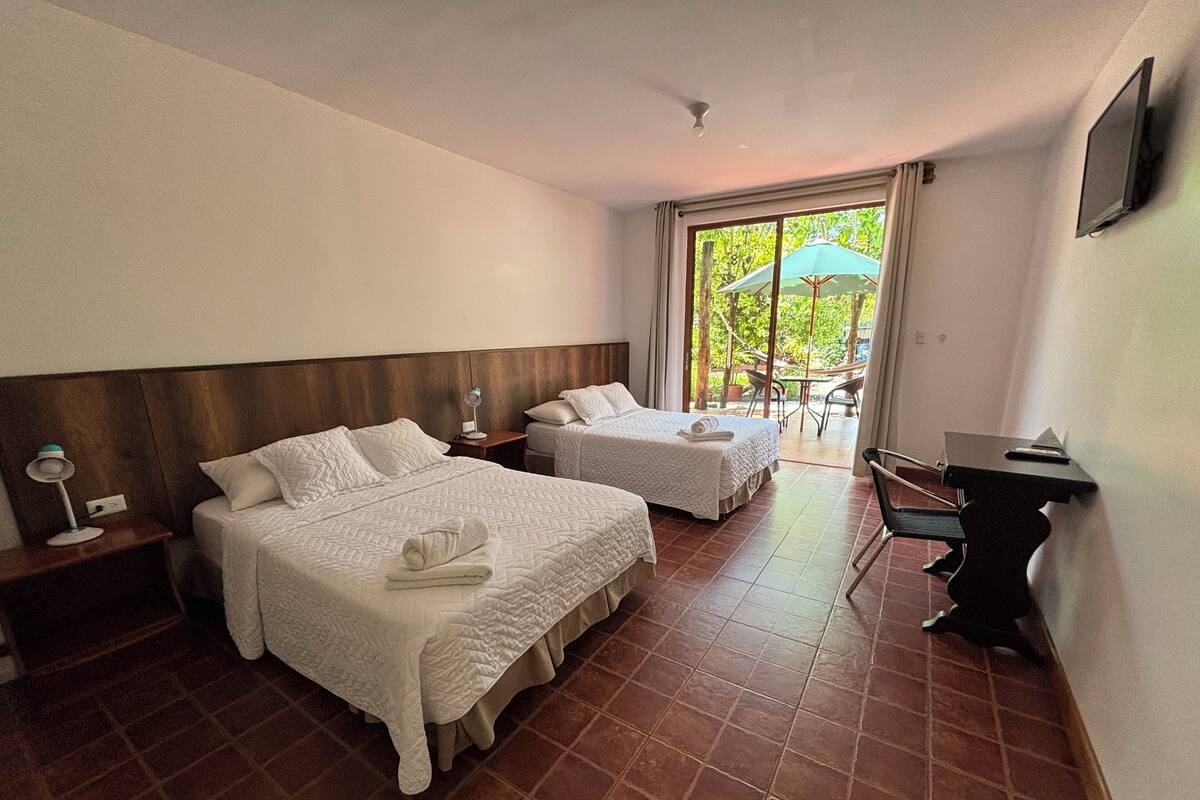 Habitación de hotel con dos camas, un escritorio y vistas al exterior.