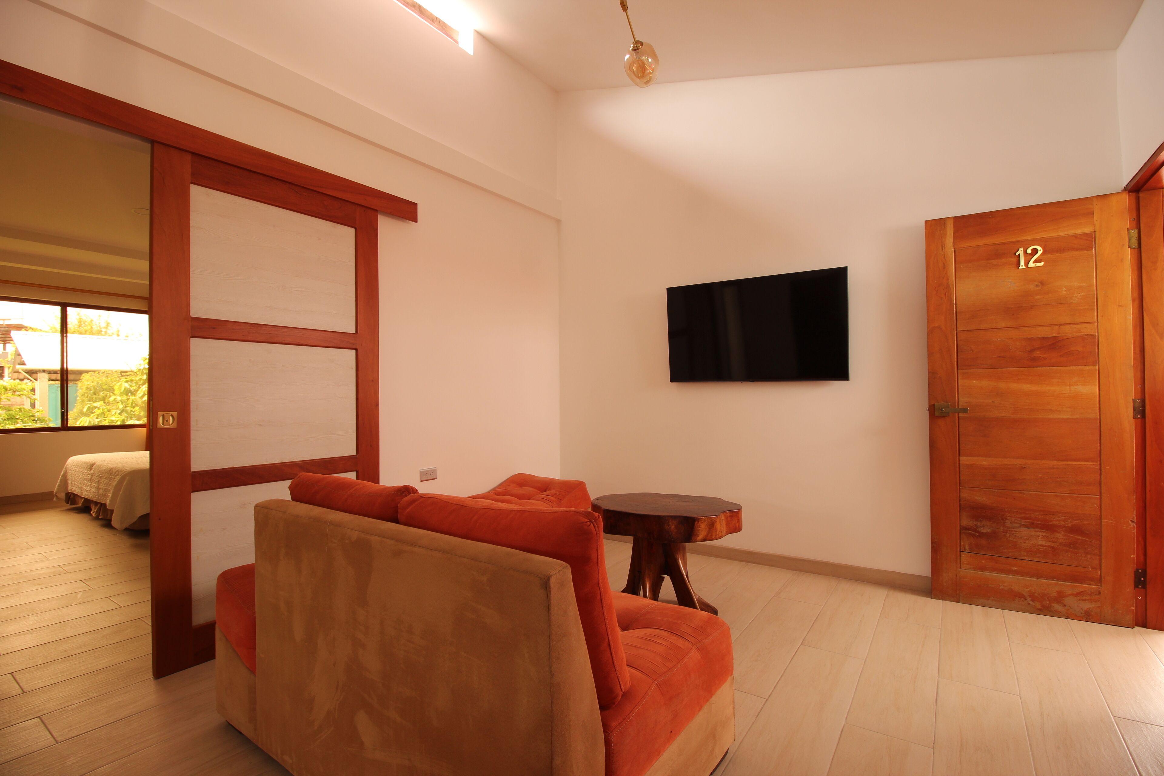 Una habitación con un sofá, un televisor en la pared y una puerta de madera con el número 12.