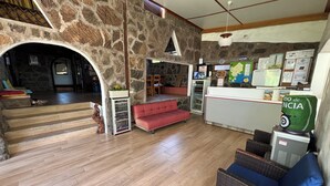 Eine Lobby mit Steinwand, einem Empfangsbereich, einem roten Sofa und einem Korbstuhl.