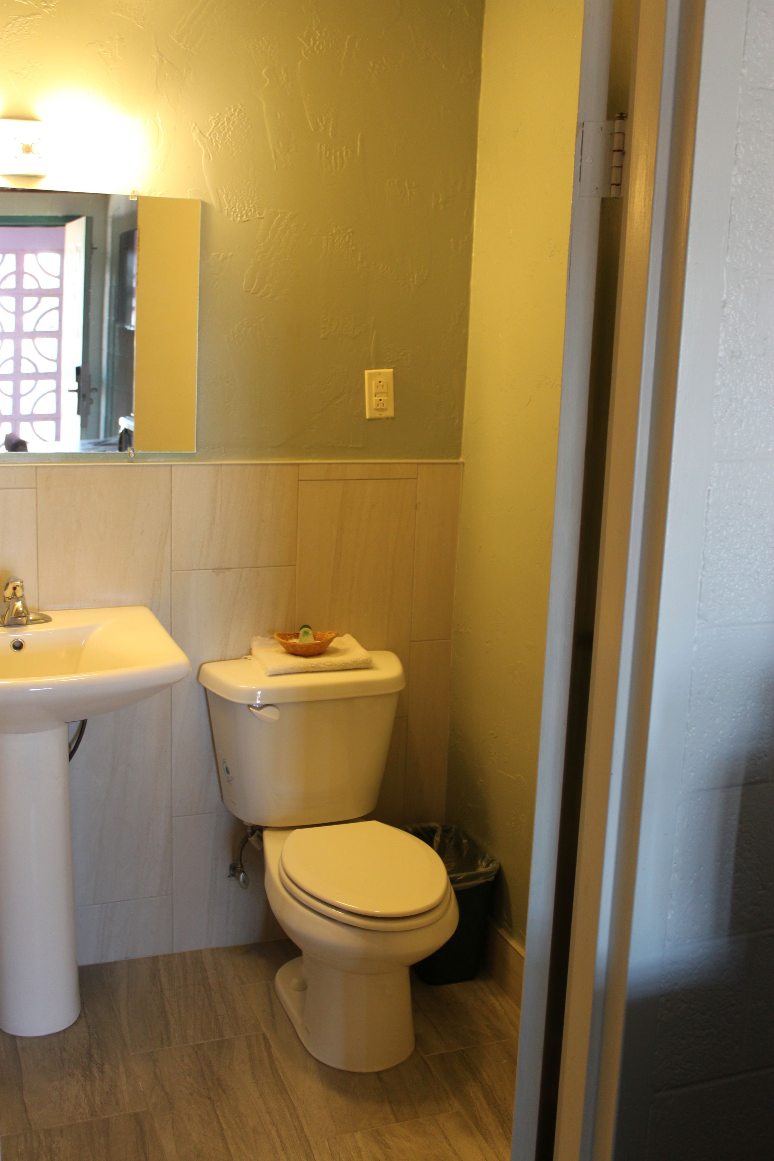 Une salle de bain avec un lavabo, des toilettes et une poubelle.