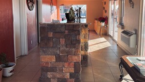 A spacious lobby with a stone column, a clock, and a view of the outside. - Century 21 Motel (Las Cruces)