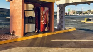 A Coca-Cola vending machine under an overpass at a gas station. - Century 21 Motel (Las Cruces)