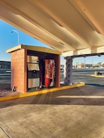 Una máquina expendedora de Coca-Cola bajo un paso elevado en una estación de servicio.
