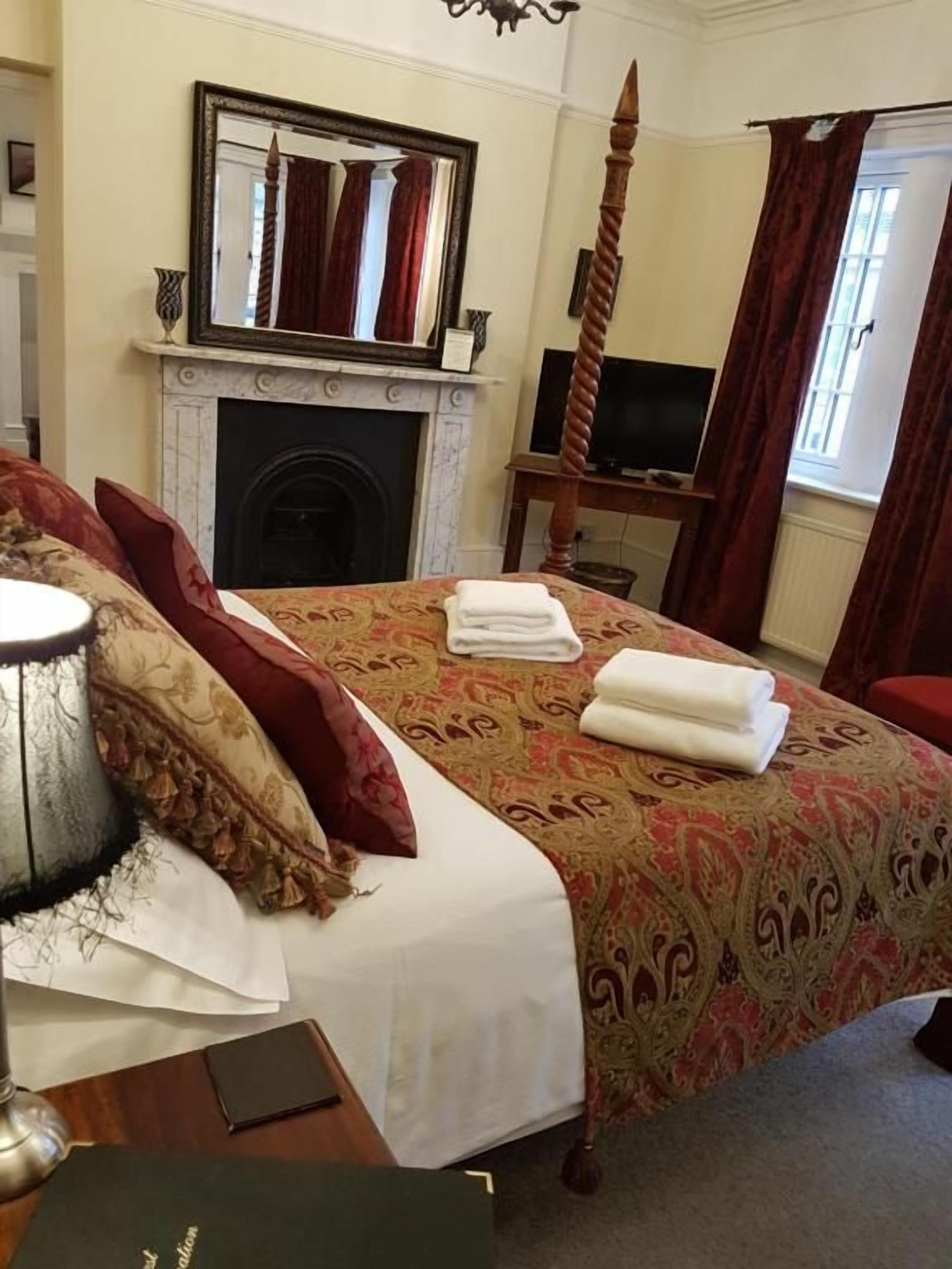 A hotel room with a bed, a television, a fireplace, and a window with curtains.