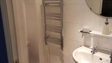 A bathroom with a toilet, a sink, a mirror, and a towel rack.