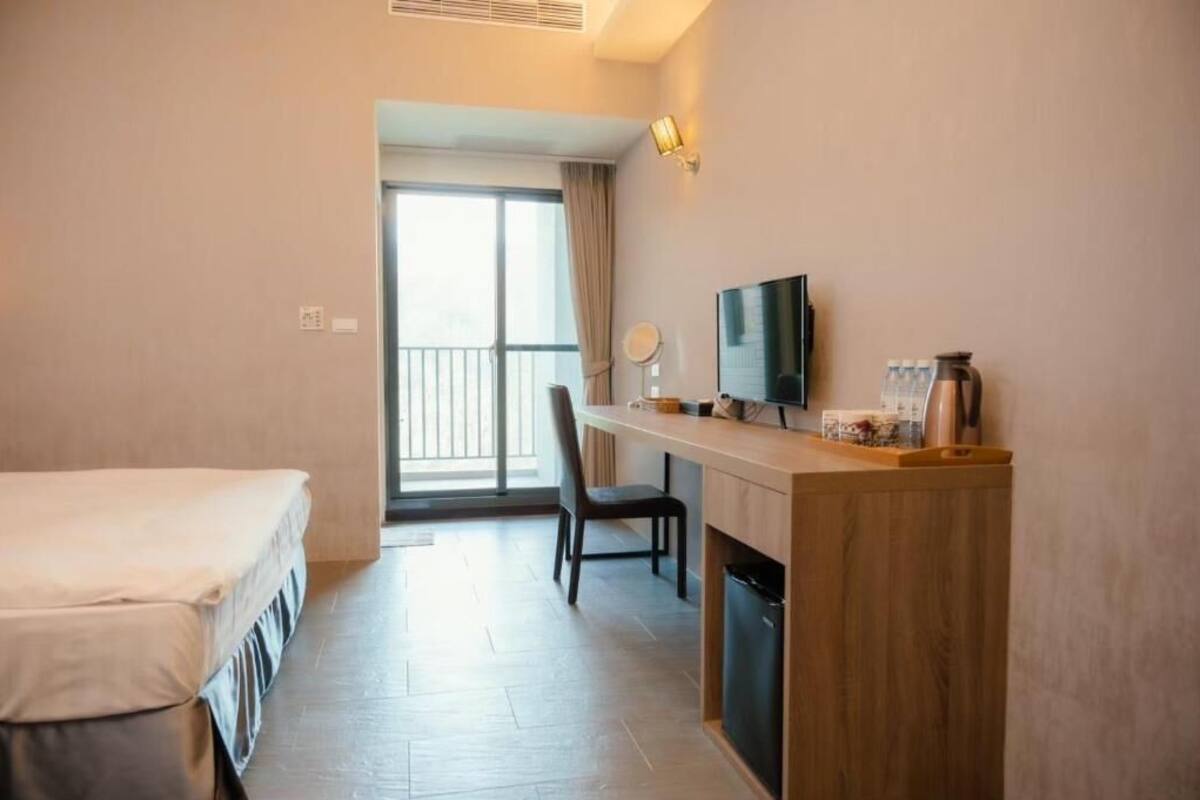 A hotel room with a bed, a desk with a television, a chair, and a coffee maker.