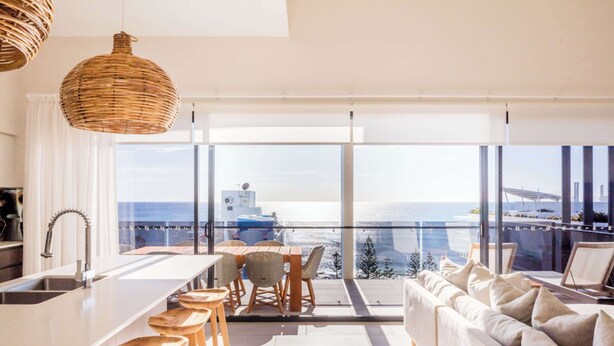 A modern kitchen with a large island, wooden stools, and a view of the sea through large windows. - First Light Mooloolaba, an Ascend Collection Hotel (Mooloolaba)