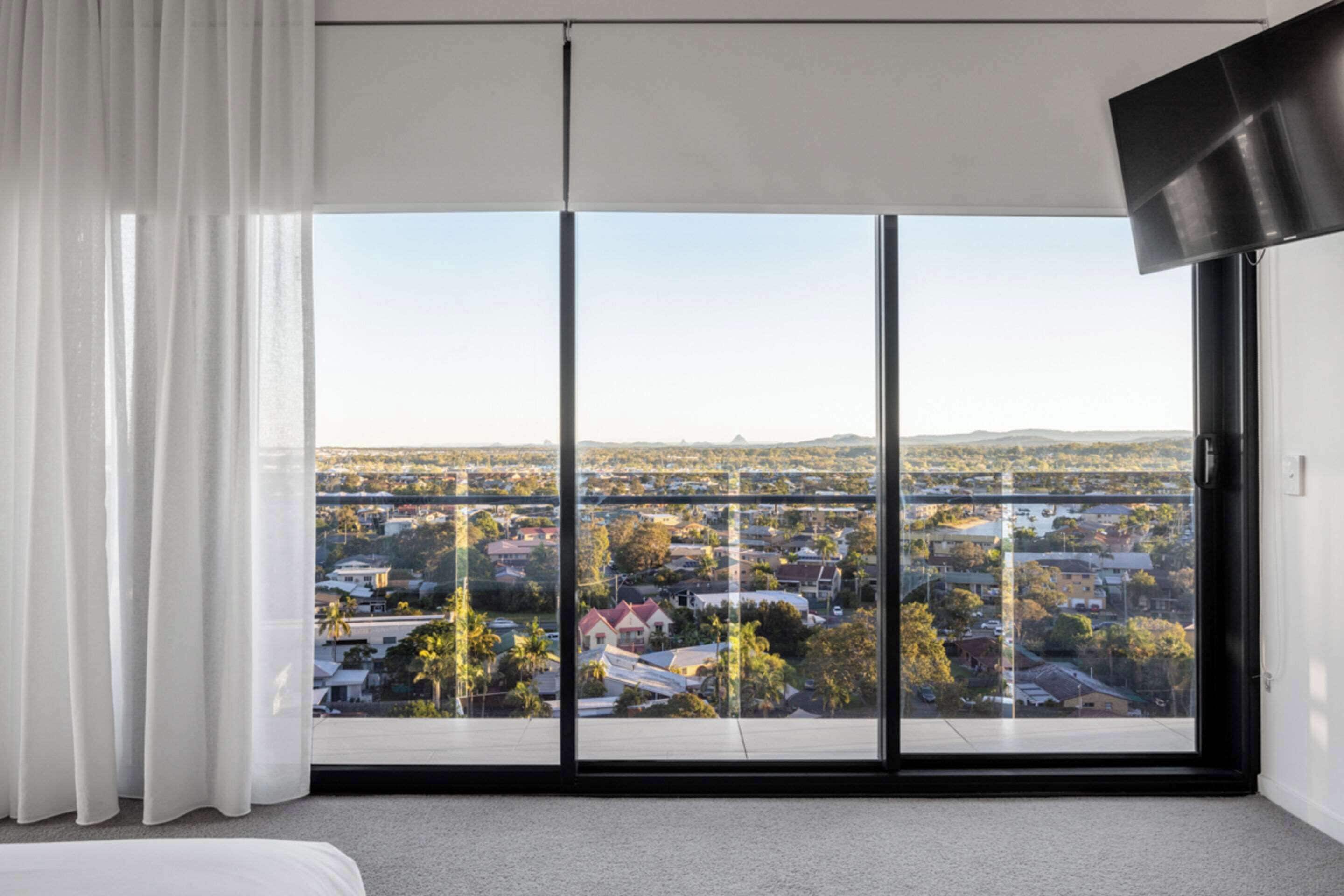 A bedroom with a large sliding glass door leading to a city view.