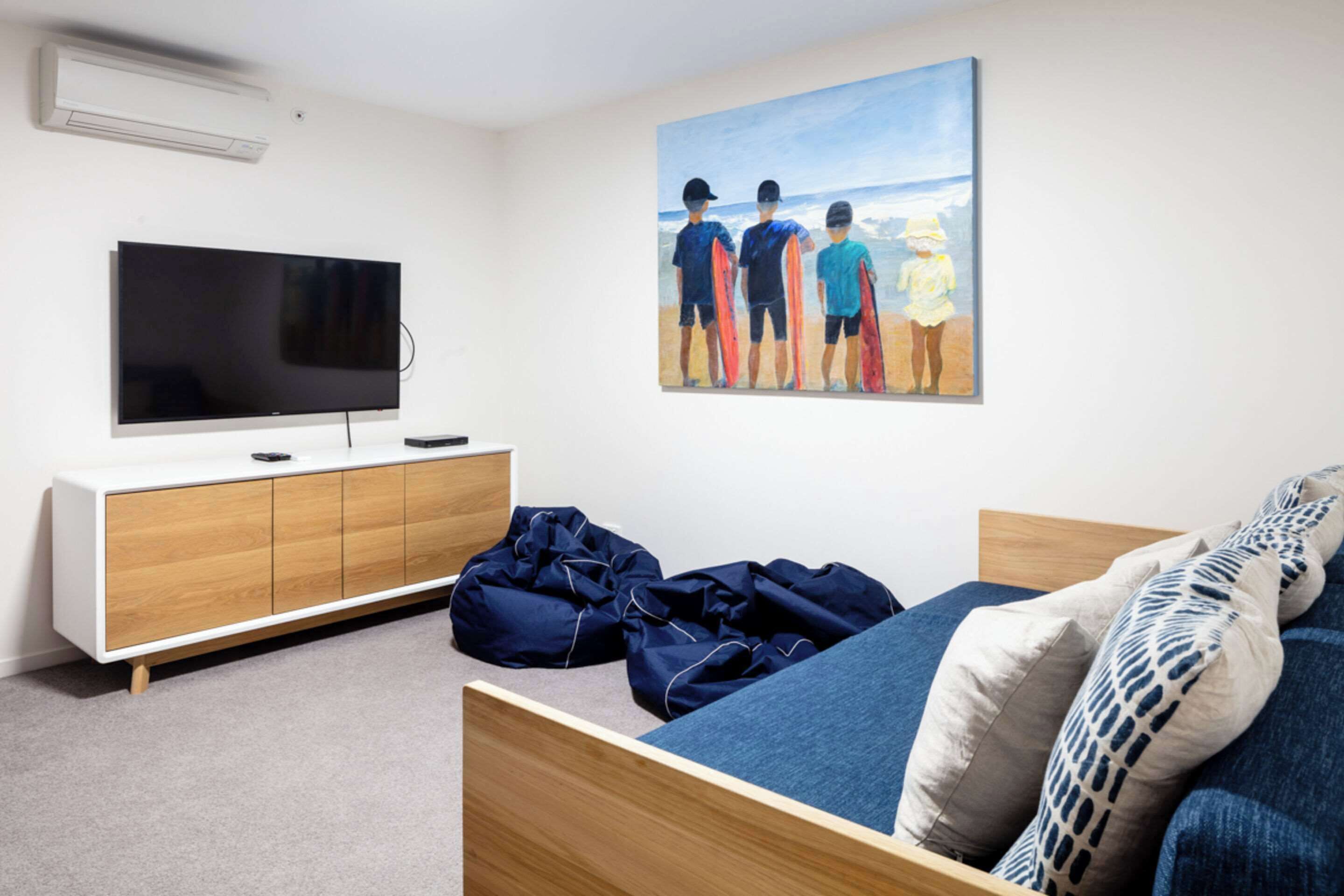 Ein Schlafzimmer mit einem Bett, einem Fernseher, einem Gemälde und einem Holzschrank.